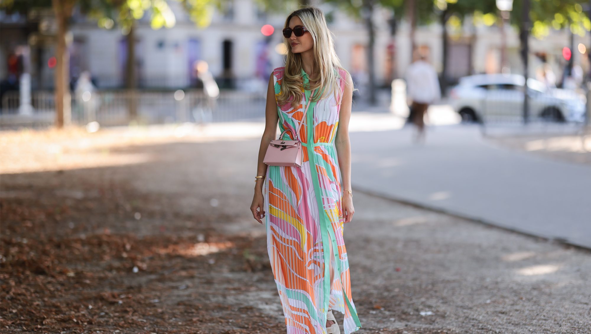 Mandy Bork seen wearing brown sunglasses from Tom Ford, a colorful buttoned / pleated / sleeveless long dress from Emilio Pucci, a pale pink Hermes Kelly mini bag and white creme sandals from Chanel, during Paris Fashion Week - Haute Couture Fall Winter 2022 2023, on July 06, 2022 in Paris, France.